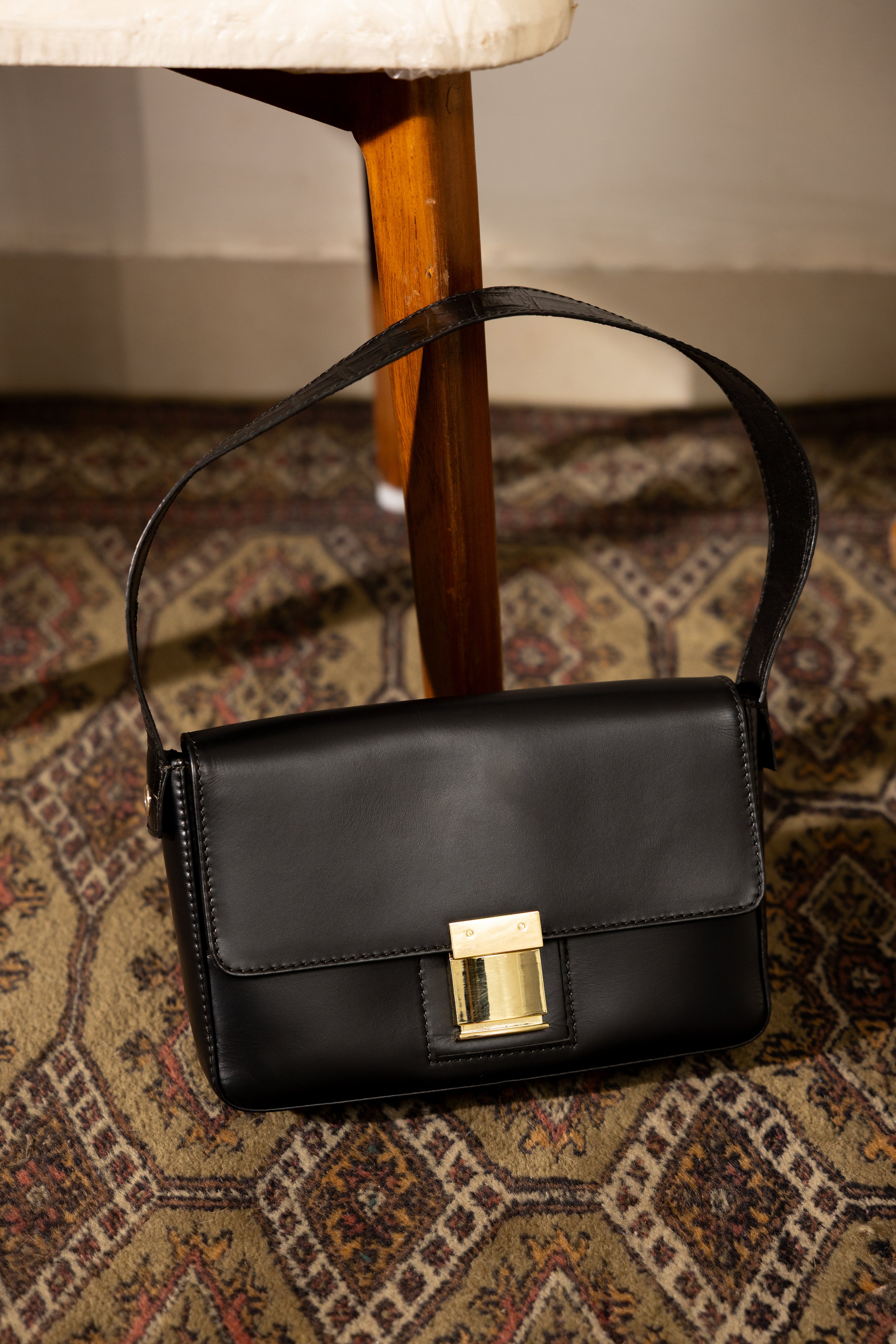 Black leather handbag featuring custom gold clasp